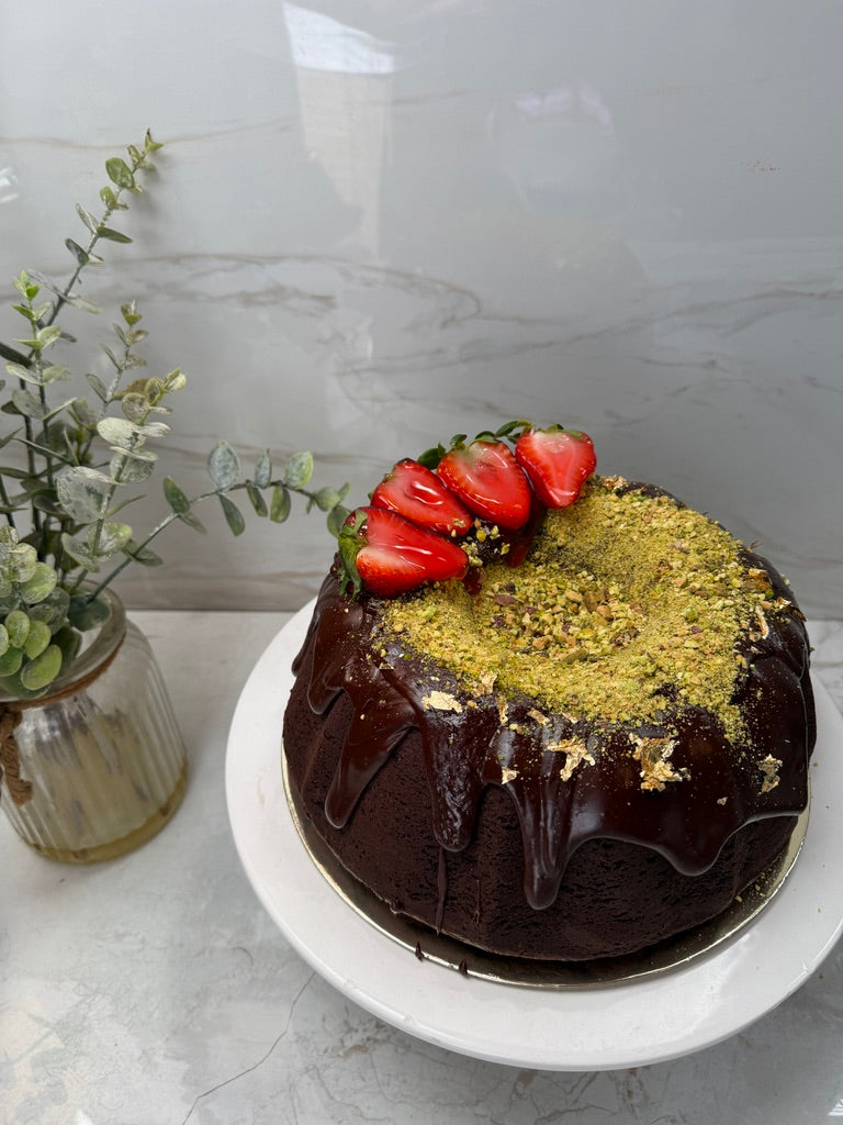 Chocolate bundt with chocolate drip, pistachio crumble and strawberries